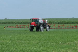 Tractor with sprayer attachment in a grassy field