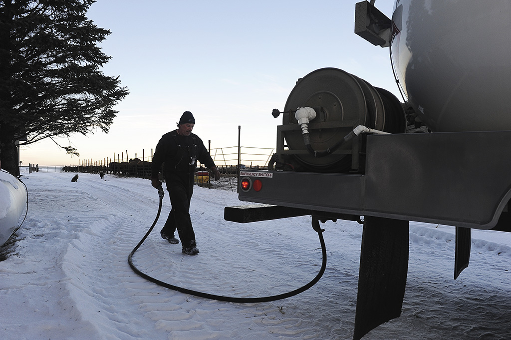Man walking hose back to propane truck in the winter