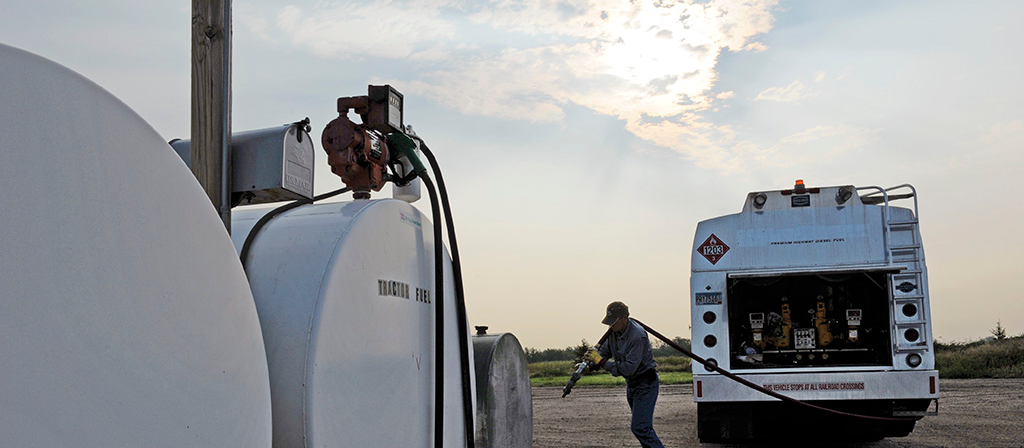 Man walking hose from propane truck to refill tanks
